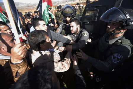 Palestinian minister Ziad Abu Ein (C) scuffles with an Israeli border policeman near the West Bank city of Ramallah December 10, 2014. REUTERS/Mohamad Torokman
