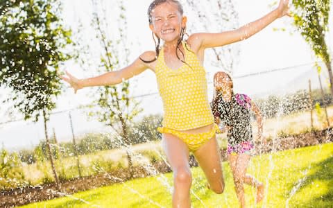 girls playing in sprinkler in backyard - Credit: Mike Kemp/Blend Images