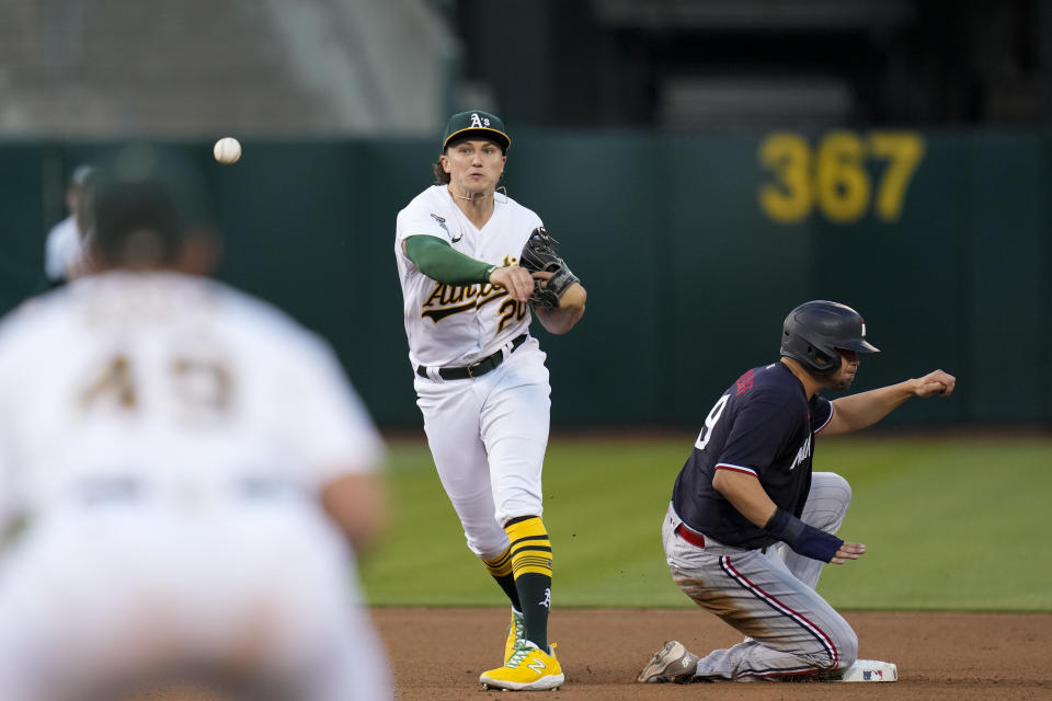 Oakland Athletics second baseman Zack Gelof, center, throws to first base after forcing out Minnesota Twins' Alex Kirilloff, right, at second during the fourth inning of a baseball game Friday, July 14, 2023, in Oakland, Calif. Twins' Christian Vázquez reached first on the play. (AP Photo/Godofredo A. Vásquez)