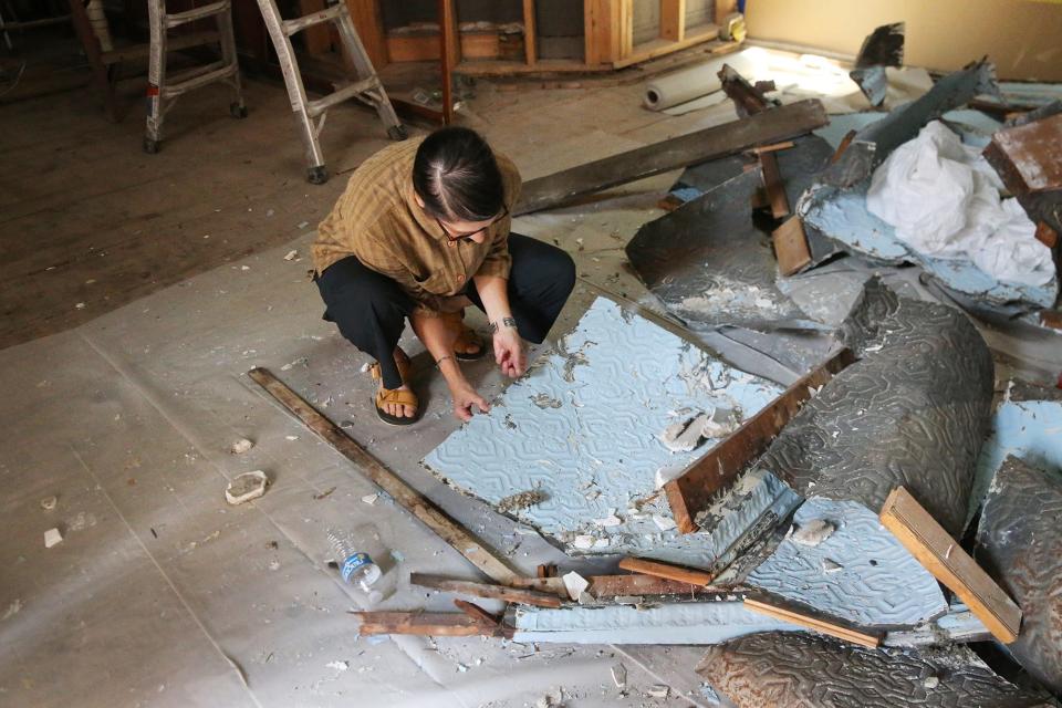 Portsmouth Brewery co-owner Joanne Francis sifts through debris Monday, July 24, 2023, from the tin ceiling that was ruined due to a burst sprinkler pipe in June.