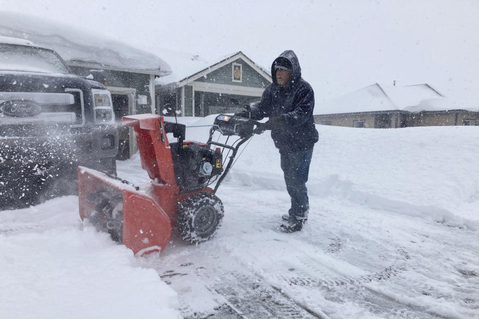Tony Delafield works to clear his driveway of snow in Bellemont, Ariz., on Wednesday, March 1, 2023. In Arizona, snow began falling Wednesday morning as the storm moved eastward and was poised to dump as much as 2 feet (60 centimeters) of snow in northern Arizona by Thursday morning. (AP Photo/Felicia Fonseca)