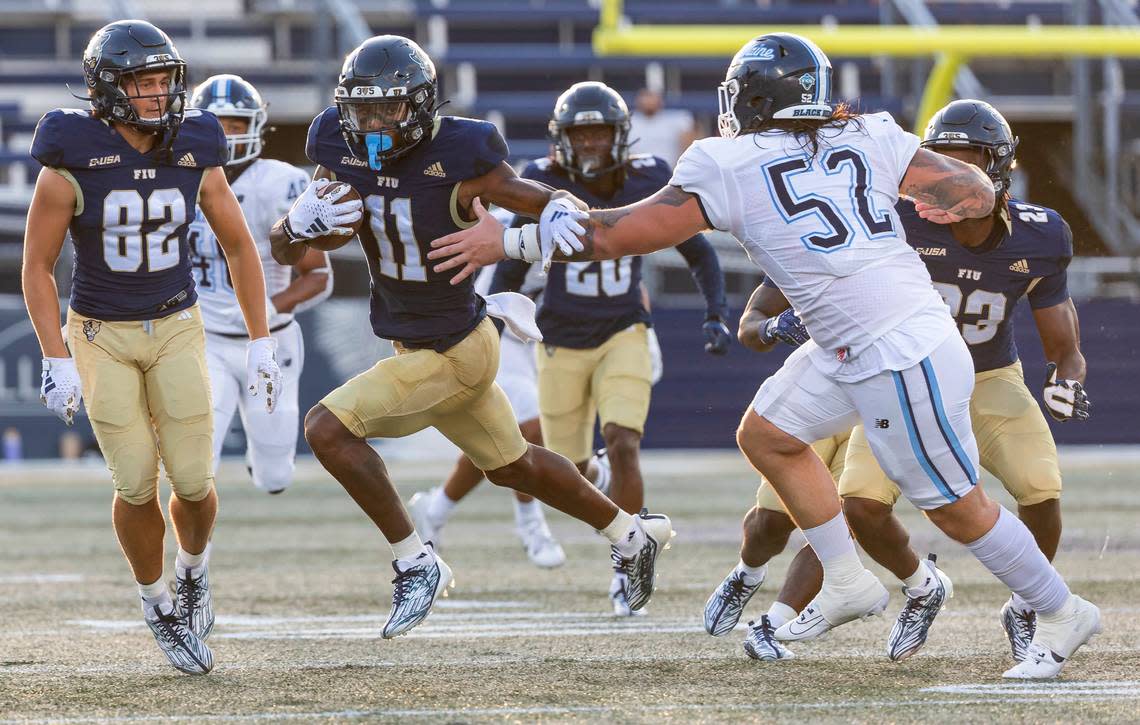 FIU Panthers wide receiver Dean Patterson (11) runs with the ball as Maine Black Bears defensive lineman John Costanza (52) tries to tackle him in the first quarter of their NCAA DI football game at the FIU Football Stadium on Saturday, Sept. 2, 2023, in Miami, Fla.