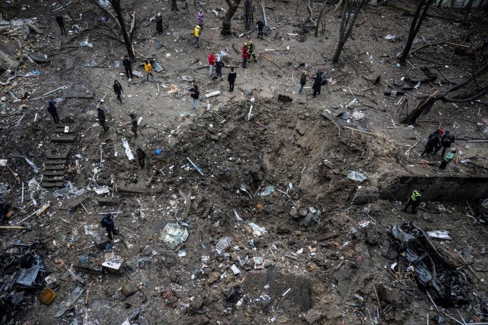 People stand next to a crater at a site of a Russian missile strike in Kyiv (Reuters)