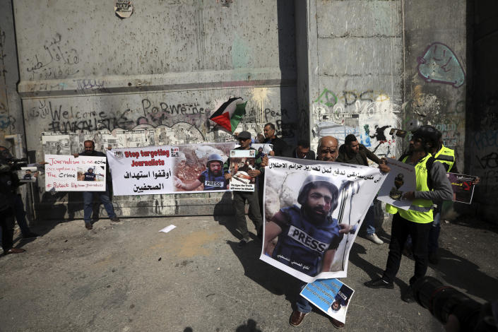 Palestinian journalist hold posters of a 35 year-old photographer Muath Amarneh in front of a separation barrier in Bethlehem, West Bank, Sunday, Nov. 18, 2019, during a protest in support . Amarneh's relatives say he has lost vision in one eye after apparently being struck by Israeli fire while covering a demonstration in the West Bank. Israel's paramilitary border police unit says it did not target him. (AP Photo/Mahmoud Illean)
