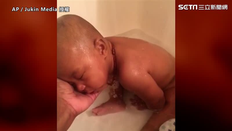 寶寶在睡覺時尿了床，媽媽便把還在熟睡的他抱下床到浴室盥洗（圖／AP／Jukin Media 授權）