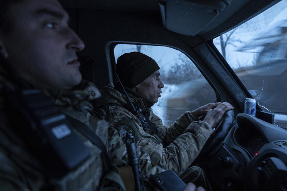 Ukrainian police officers of the White Angels unit, ride in a van to distribute humanitarian aid to local residents in Krasnohorivka, Ukraine, Friday, Feb. 17, 2023. A special unit known as the White Angels risk their lives to head into front-line villages and towns, knocking on doors and pleading with the few remaining residents to evacuate. (AP Photo/Evgeniy Maloletka)