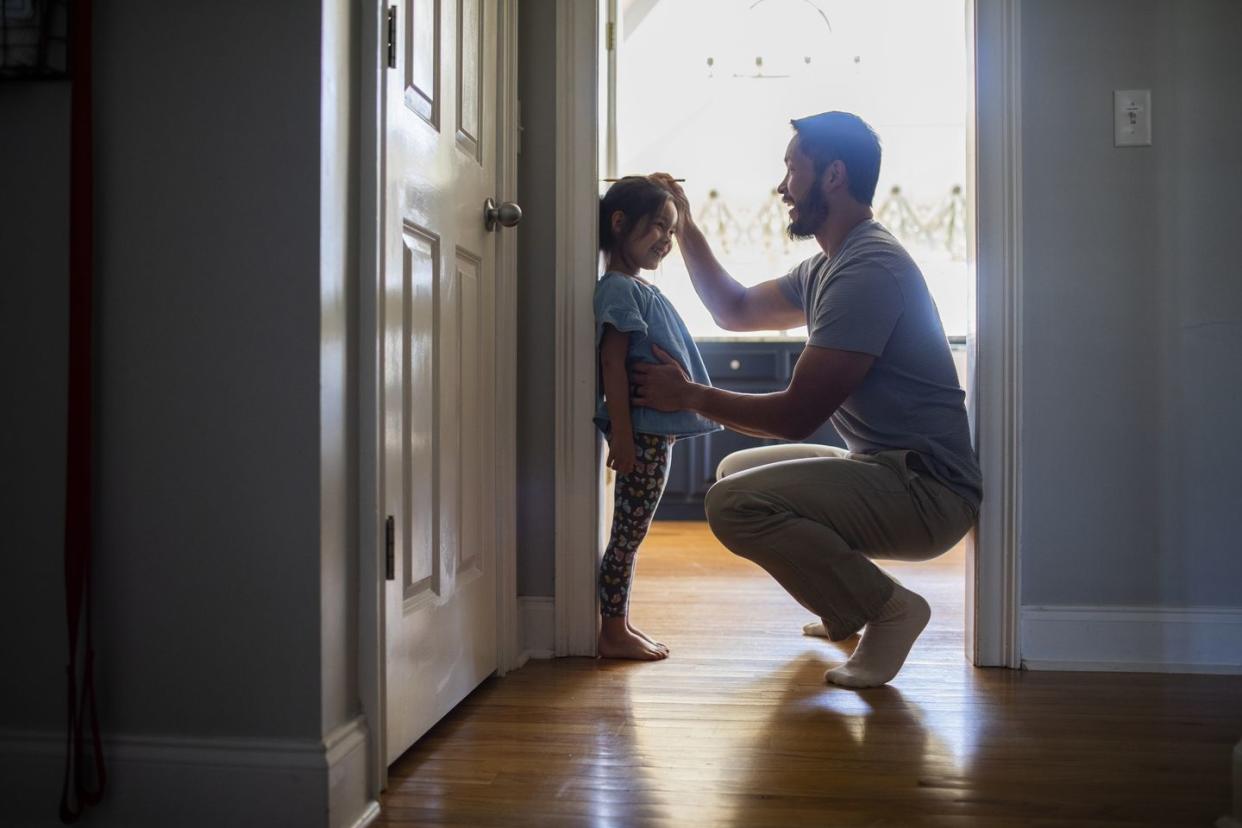 father measuring daughters height against wall