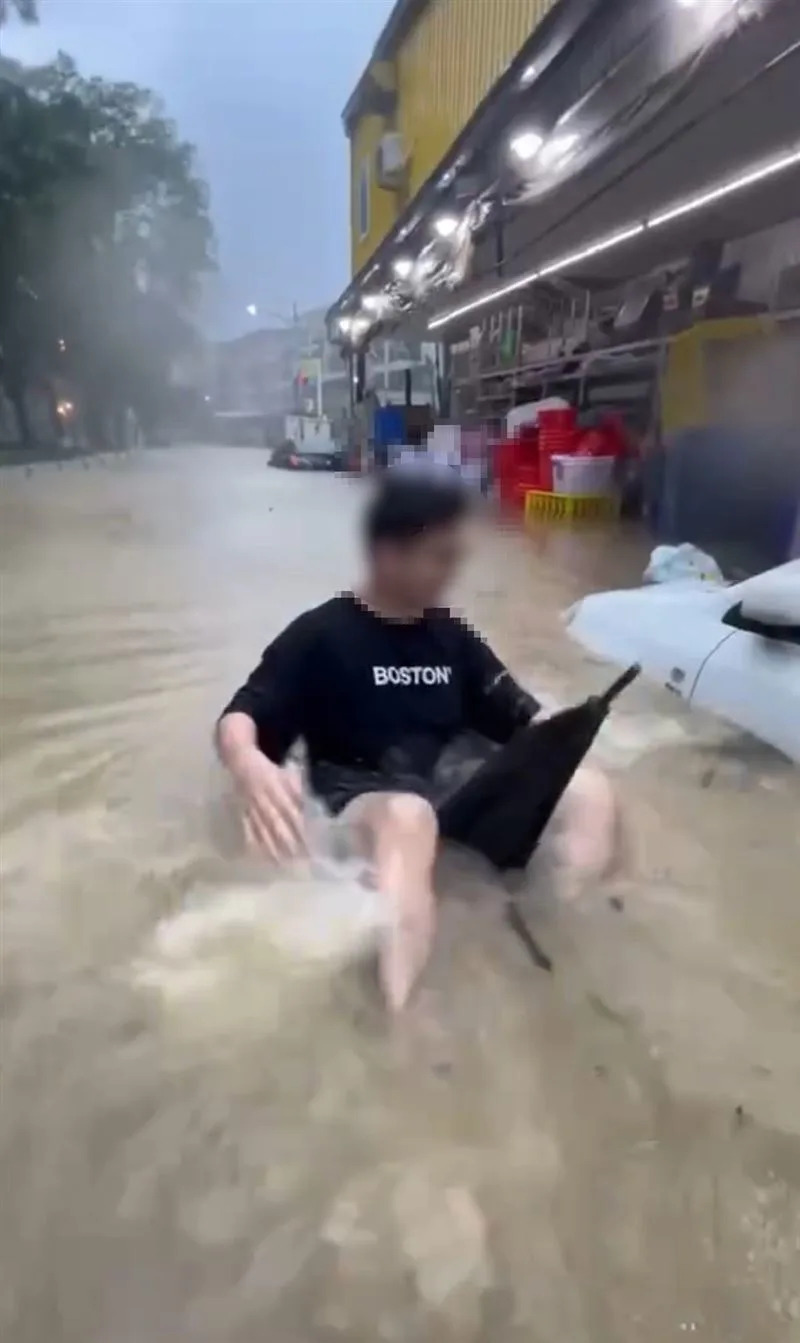 高雄市仁武區也水淹半個車身高，有民眾拿泳圈「游」回家。（圖／翻攝畫面）