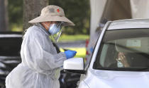 A medical professional prepares to apply a nasal swab during testing at the Orange County Health Services COVID-19 drive-thru site at Barnett Park in Orlando, Fla., Thursday, Oct. 29, 2020. The free tests are available 8am to 1pm daily at the park adjacent to the Central Florida Fairgrounds on West Colonial Drive. (Joe Burbank /Orlando Sentinel via AP)