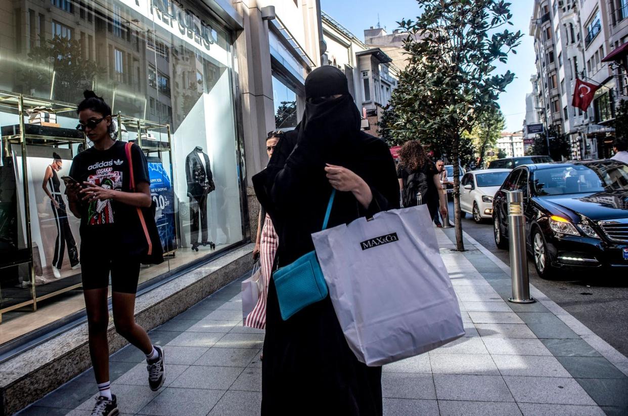 <span class="caption">A woman wearing a niqab and headscarf, with other shoppers in Istanbul, August 13, 2018. </span> <span class="attribution"><a class="link " href="https://www.gettyimages.com/detail/news-photo/woman-wearing-a-niqab-holds-shopping-bags-as-she-walks-in-news-photo/1016425444?adppopup=true" rel="nofollow noopener" target="_blank" data-ylk="slk:YASIN AKGUL/AFP via Getty Images;elm:context_link;itc:0;sec:content-canvas">YASIN AKGUL/AFP via Getty Images</a></span>