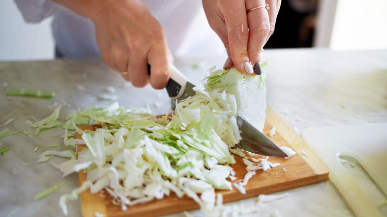 Hands slicing cabbage into strips