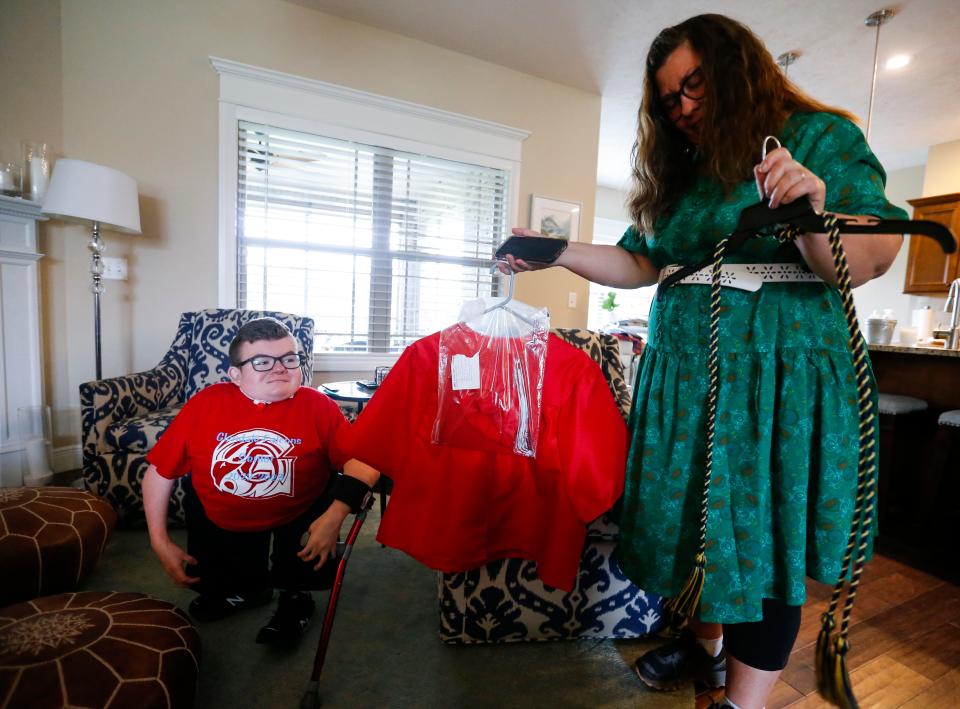 Nikki Dugger, a nurse, shows off the Glendale High School graduation cap and gown for Collin Langston.