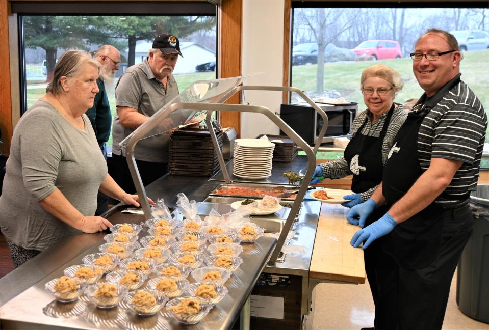 Helen Sturtz and nutrition director Mike Searing serve senior hot meals at the Burnside Center congregate meal program.