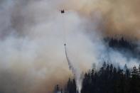 In this Sept. 3, 2020, photo provided by the Opal Creek Ancient Forest Center, fire retardant is dropped at Jawbone Flats in the Opal Creek Wilderness in Oregon. Oregonians are grieving the loss of some of their most treasured natural places after wildfires wiped out campgrounds, hot springs and wooded retreats that have been a touchstone for generations in a state known for its unspoiled beauty. (Augustus Gleason/Opal Creek Ancient Forest Center via AP)