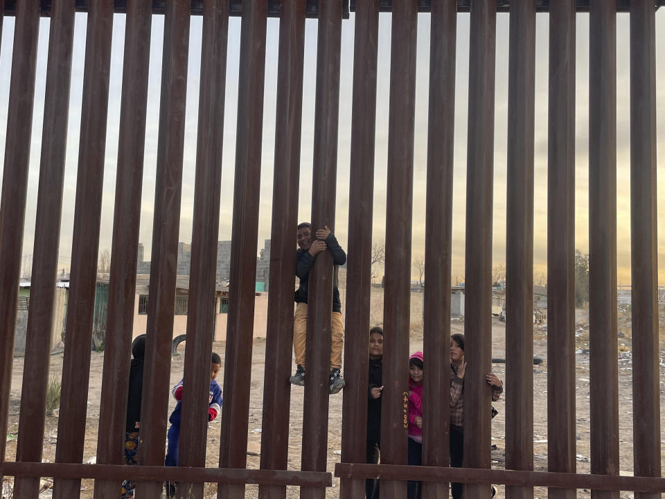 A few miles west of where the Texas National Guard deployed on the U.S.-Mexico border, a few children play by the fence on the Mexican side in the desert scrub across from Sunland Park, N.M., Tuesday, Dec. 20, 2022. (AP Photo/Giovanna Dell'Orto)