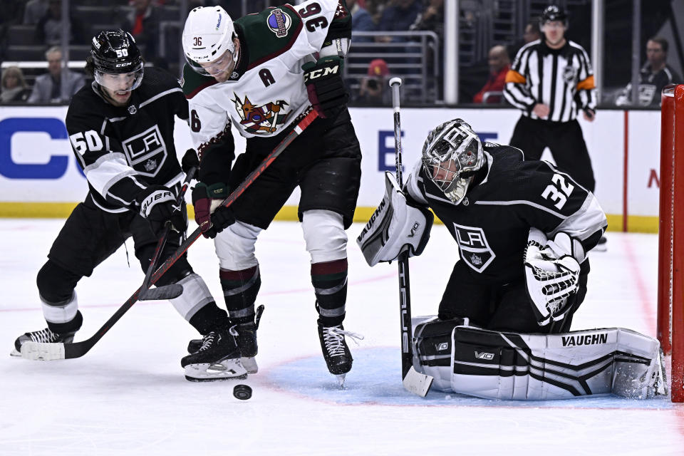 Arizona Coyotes right wing Christian Fischer, center, vies for the puck with Los Angeles Kings defenseman Sean Durzi, left, in front of goaltender Jonathan Quick during the third period of an NHL hockey game in Los Angeles, Thursday, Dec. 1, 2022. (AP Photo/Alex Gallardo)