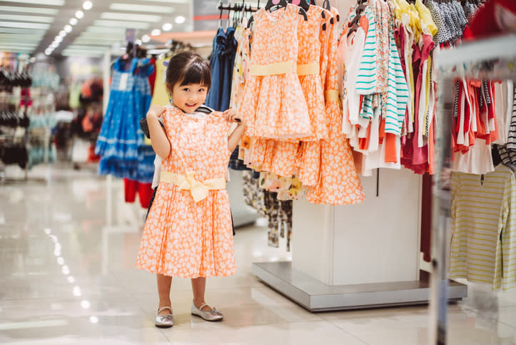 A little girl modeling a dress in a clothing store