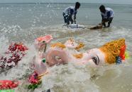 <p>Indian devotees immerse an idol of the elephant-headed Hindu god Ganesh in the Indian ocean at Pattinapakkam beach in Chennai on September 16, 2018, as part of Ganesh Chaturthi festival. (Photo by ARUN SANKAR/AFP/Getty Images) </p>