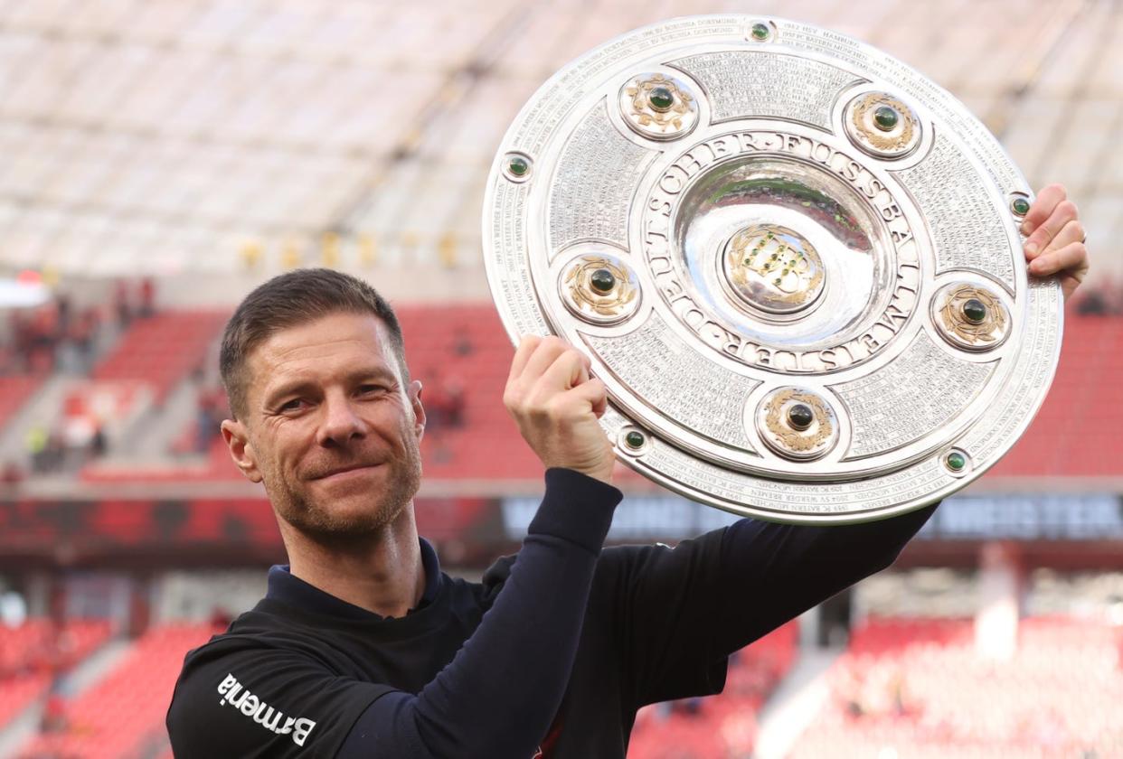 xabi alonso holds up the bundesliga trophy and smiles