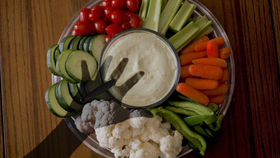 a veggie tray with a shadowed hand over it