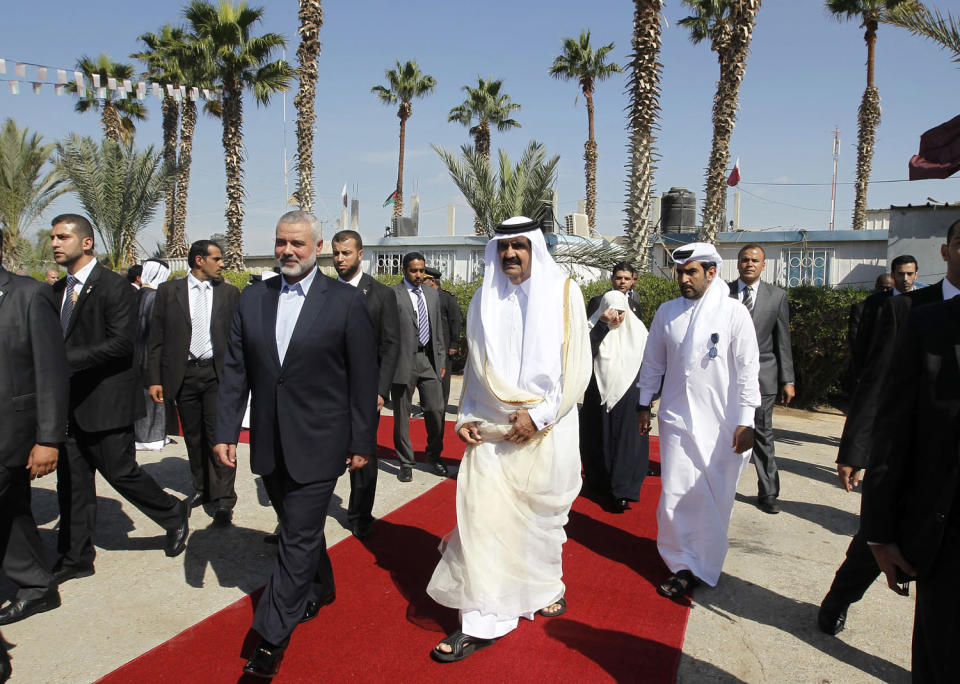 Gaza's Hamas Prime Minister Ismail Haniya, center left, walks alongside Qatari Emir Sheikh Hamad bin Khalifa al-Thani during a welcome ceremony (Mohammed Abed / Pool / AFP via Getty Images file)