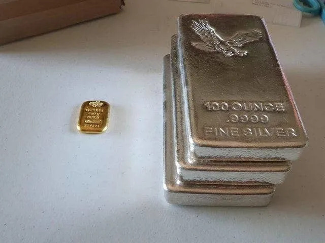 A small block of gold versus three 100-ounce fine-silver stacks