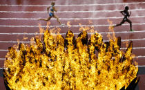 <p>Runners pass the Olympic torch on the first day of competition at the 2012 Summer Olympics, London, Aug. 3, 2012. (Photo: Daniel Ochoa de Olza/AP) </p>