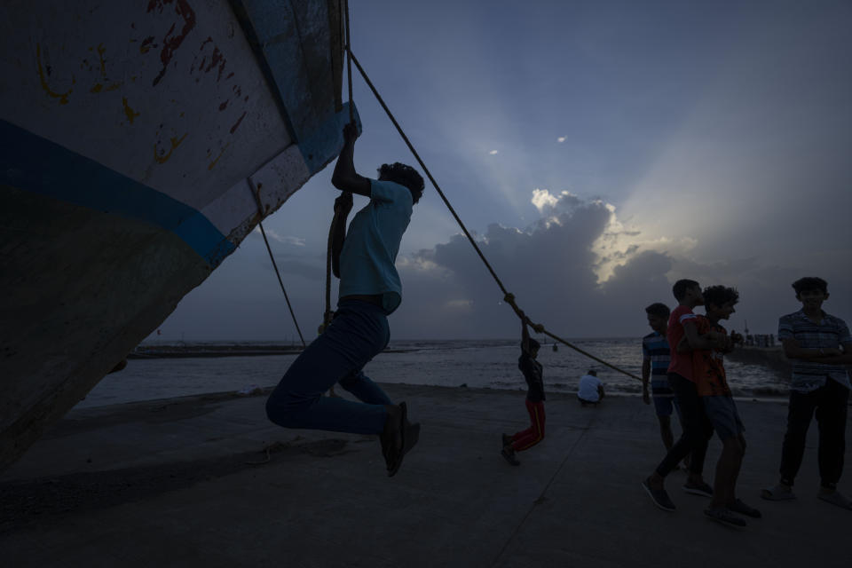 Boys play with the ropes of an anchored fishing boat as high tide waves hit the Arabian Sea coast at Juhu Koliwada in Mumbai, India, Monday, June 12, 2023. Cyclone Biparjoy, the first severe cyclone in the Arabian Sea this year is set to hit the coastlines of India and Pakistan Thursday. (AP Photo/Rafiq Maqbool)