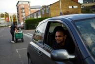 Suman Uththamaputhir, a resident of the Carpenters Estate in Stratford waits to receive food bank donations from volunteer Kingsley Ellis as the spread of the coronavirus disease (COVID-19) continues, in east London