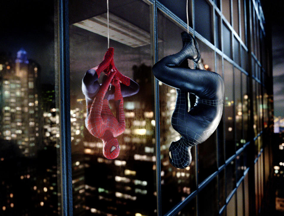 Spider-Man and Venom hanging upside down and looking at each other through a building window