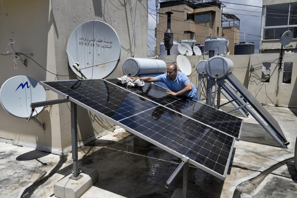 A man cleans solar panels installed on the roof of a building in Beirut, Lebanon, Thursday, May 30, 2024. Lebanese caretaker Minister of Economy and Trade Amin Salam said Lebanon's political class as well as fuel companies and private electricity providers in Lebanon blocked an offer by gas-rich Qatar to build three renewable energy power plants to ease the crisis-hit nation's decades-old electricity crisis. (AP Photo/Bilal Hussein)