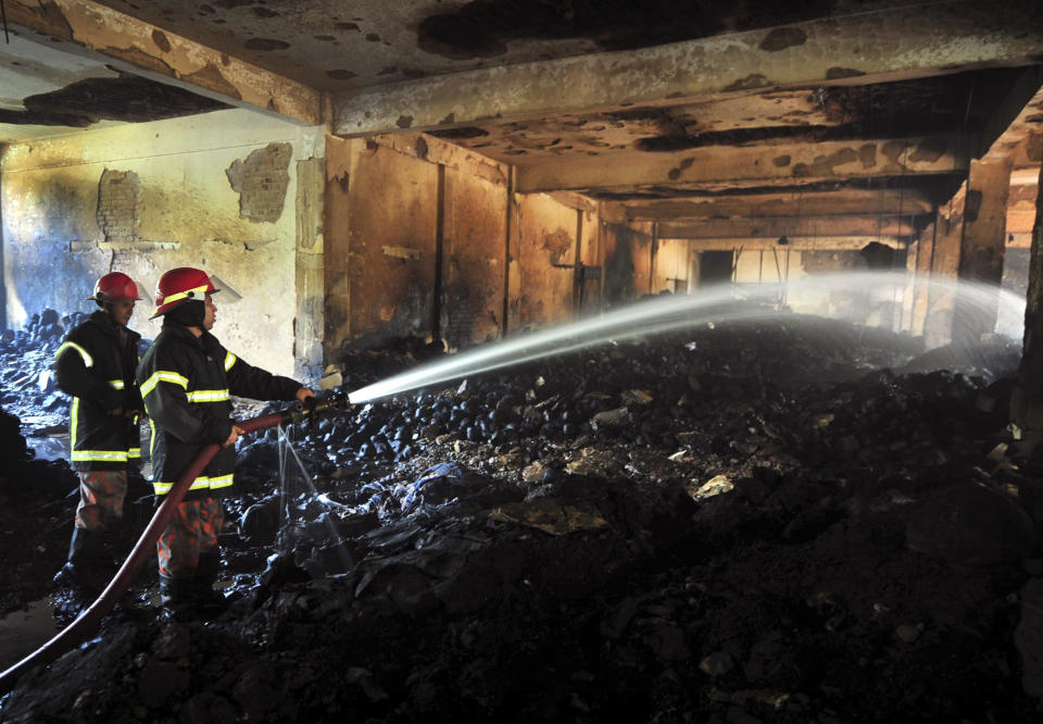 Bangladeshi firefighters douse last of the smoke at the garment factory outside Dhaka, Bangladesh, Sunday Nov. 25, 2012. At least 112 people were killed in a late Saturday night fire that raced through the multi-story garment factory just outside of Bangladesh's capital, an official said Sunday. (AP Photo/ khurshed Rinku)