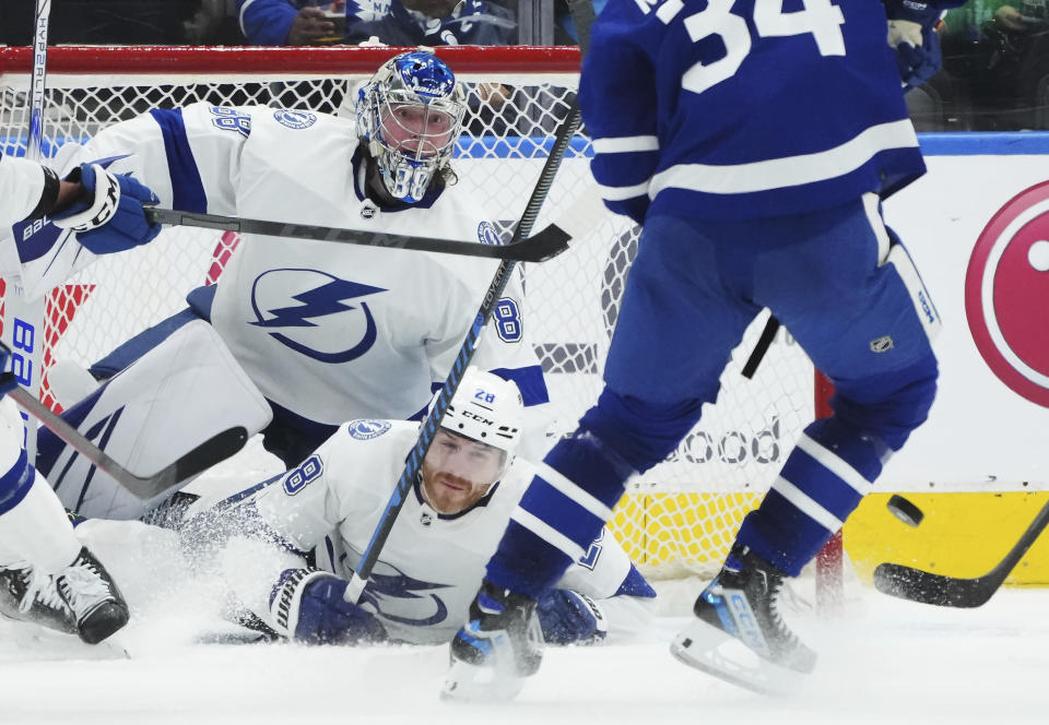 Tampa Bay Lightning goaltender Andrei Vasilevskiy (88) watches the puck on a shot from Toronto Maple Leafs forward Auston Matthews (34) as Lightning defenseman Ian Cole (28) falls to the ice during the third period of Game 1 of a first-round NHL hockey playoff series Tuesday, April 18, 2023, in Toronto. (Nathan Denette/The Canadian Press via AP)