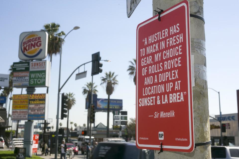 In this photo taken Friday, Feb. 21, 2014 a hip-hop themed banner is placed at the intersection of Sunset Blvd. and La Brea Ave., in Los Angeles. Street artist Jay Shells installed the sign after one day when he caught the name of a nearby intersection cited in a hip-hop song he'd been playing. Shells has put up scores of carefully drawn, hand-screened signs featuring the words of other rappers. (AP Photo/Damian Dovarganes)