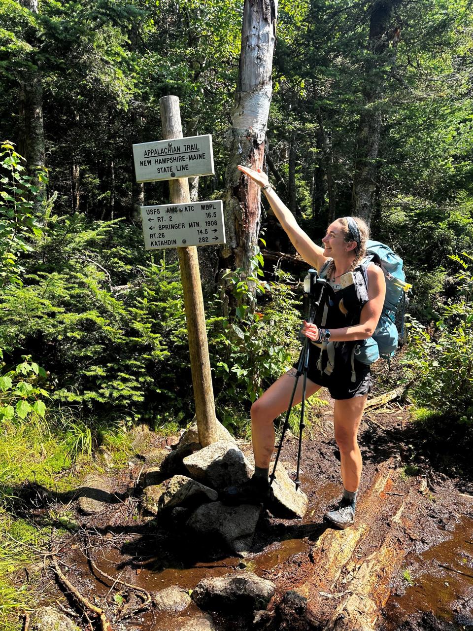 Alexis Holzmann poses at a sign indicating the New Hampshire-Maine state line during the final stretch of her hike of the Appalachian Trail this summer.