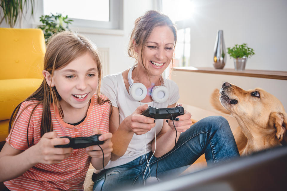 Mother and daughter playing video games on laptop at home