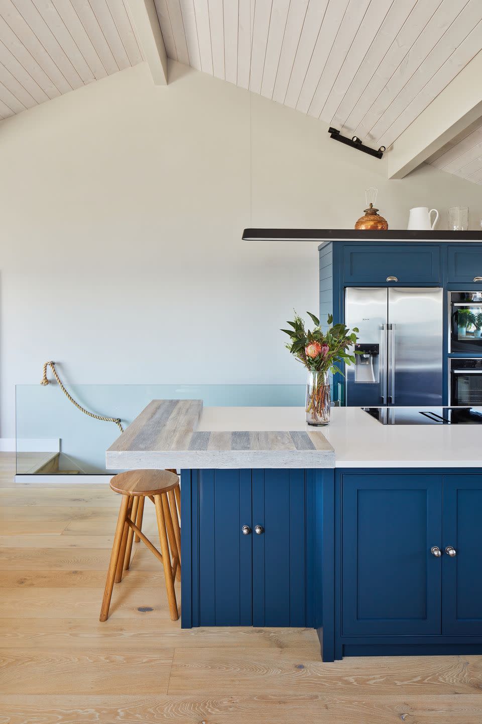 blue kitchen in coastal home with wooden floorboards and white walls