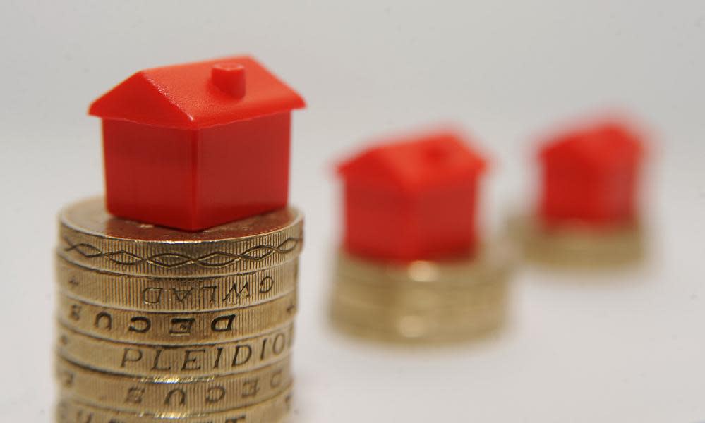 Plastic models of houses sitting on a pile of one pound coins