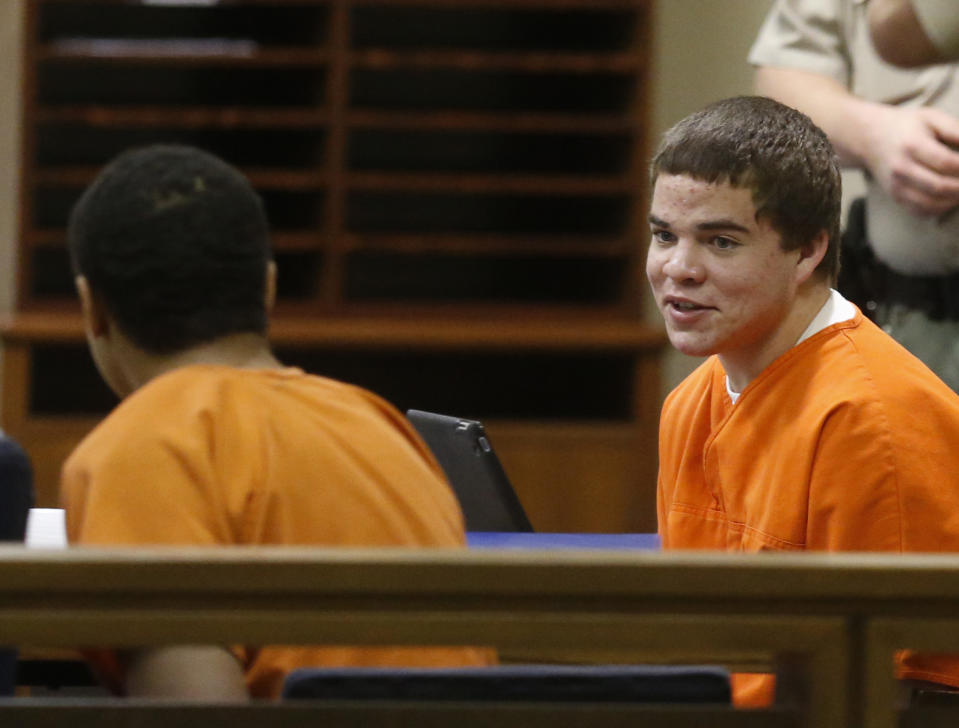 In this photo shot through a courtroom door, defendants Michael Jones, right, and Chancey Luna, left, talk in the courtroom following a hearing in Duncan, Okla, Wednesday, March 12, 2014. An Oklahoma judge ruled that the two teenagers charged with first-degree murder must face a trial in the shooting death of an Australian baseball player, Christopher Lane. (AP Photo/Sue Ogrocki)