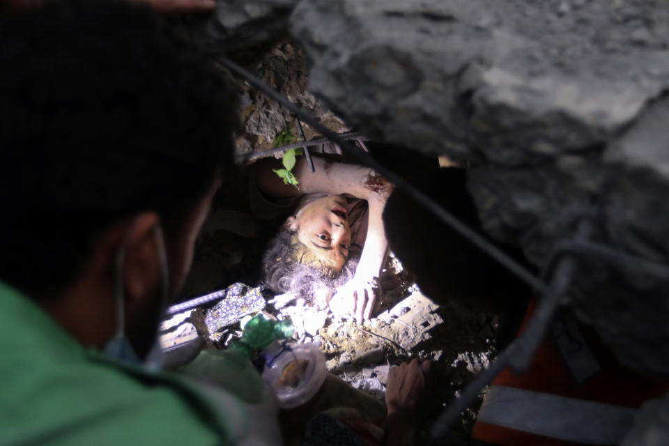 Palestinians try to rescue a girl stuck under the rubble of a destroyed building following Israeli airstrikes in Nusseirat refugee camp, central Gaza Strip, Tuesday, Oct. 31, 2023. (AP Photo/Mohammed Dahman)