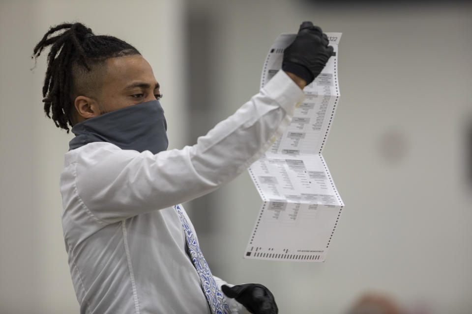 A worker with the Detroit Department of Elections inspects an absentee ballot at the Central Counting Board in the TCF Center on November 4, 2020 in Detroit, Michigan. (Elaine Cromie/Getty Images)