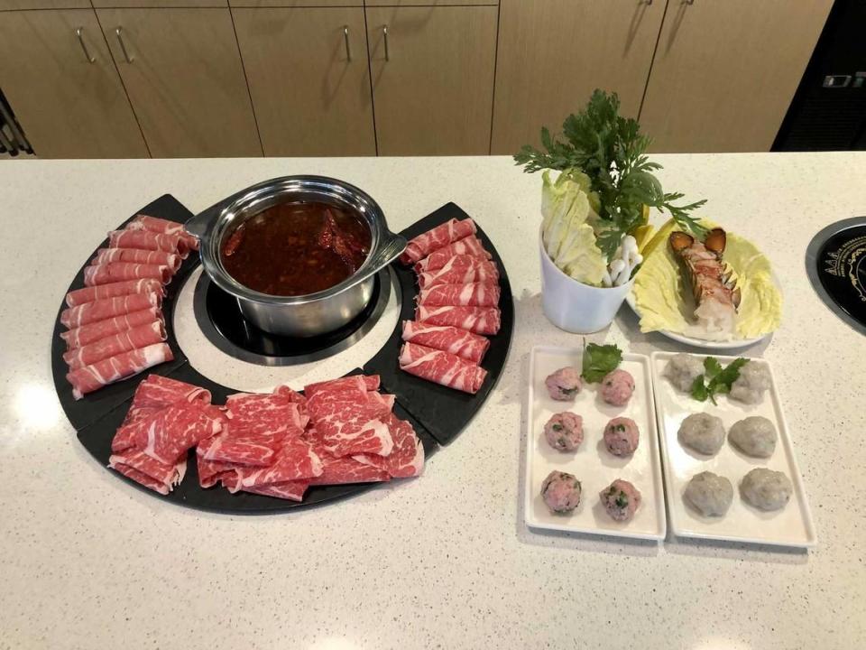 Tao’s HotPot and Shabu spicy beef broth Chongquing style surrounded by, from left to right, Australian lamb, American Kobe beef and certified Angus beef is pictured next to sides of a veggie bowl, lobster tail, shrimp balls and cilantro meatballs on Jan. 30, 2023. Owner Taobo He, 29, moved to the United States after high school, found his passion in cooking during college and opened HotPot, his first restaurant.