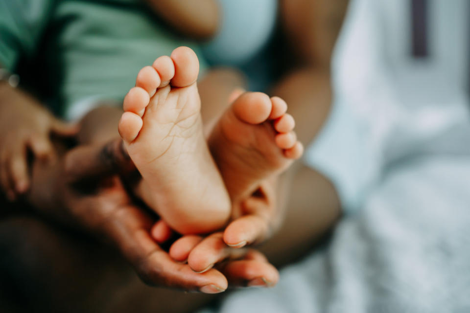 Close-up of an adult holding an infant's tiny feet in their hands, showing a tender moment between parent and baby