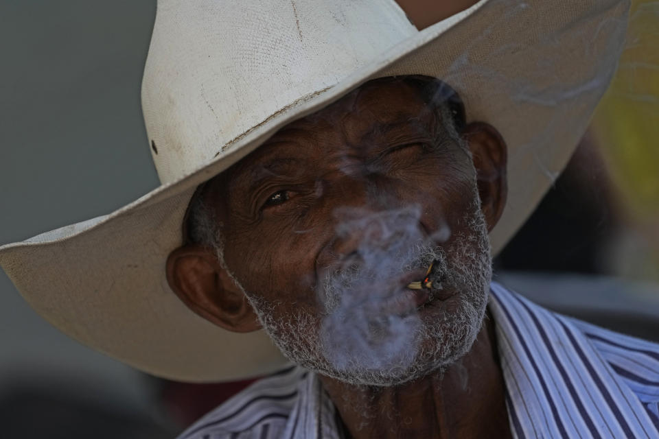 Eugenio Pereira, 81, smokes his straw cigarette at the Kalunga quilombo, in the rural area of Cavalcante in Goias state, Brazil, Monday, Aug. 15, 2022. The Kalunga quilombo villager´s ancestors settled there as runaway slaves more than 200 years ago. (AP Photo/Eraldo Peres)