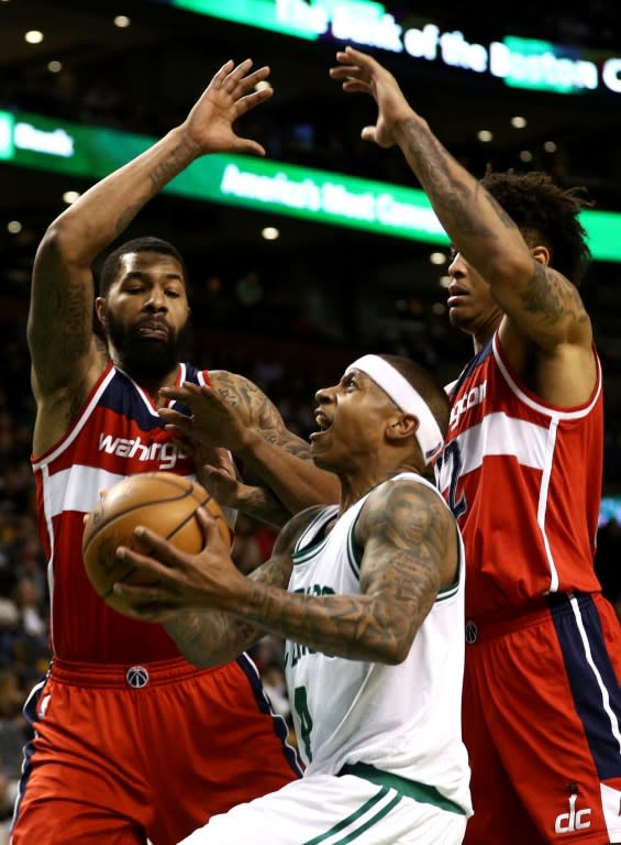 Isaiah Thomas of the Boston Celtics takes a shot against Markieff Morris (L) and Kelly Oubre Jr. of the Washington Wizards during the fourth quarter, at TD Garden in Boston, Massachusetts, on March 20, 2017