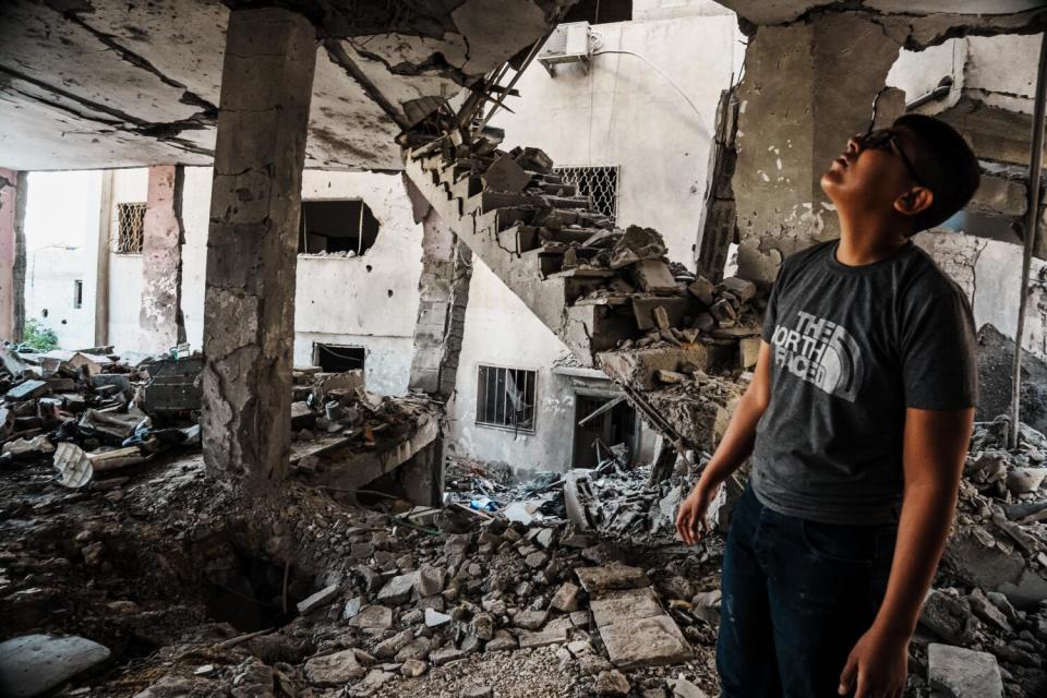 Local residents examine the aftermath of an Israeli airstrike on the Al Ansar Mosque