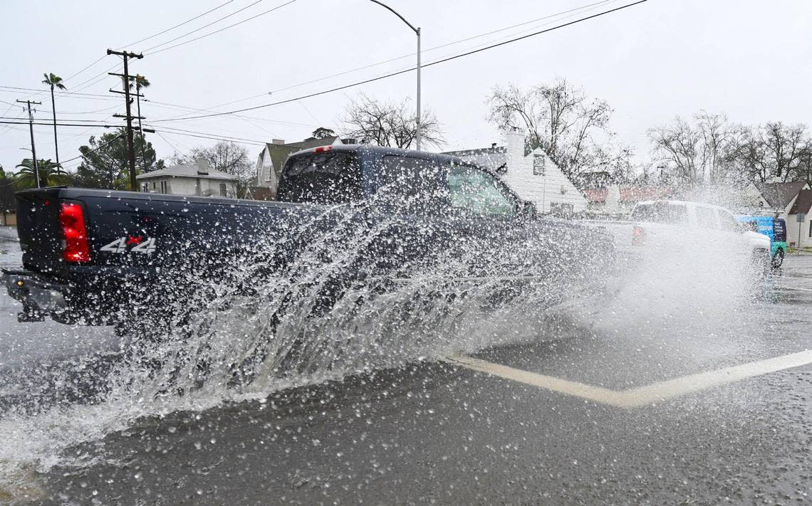 Westbound traffic along Clinton Ave. splashes through the flooded intersection at Maroa Avenue as an atmospheric river continues to dump rain Monday, Jan. 9, 2023 in Fresno.