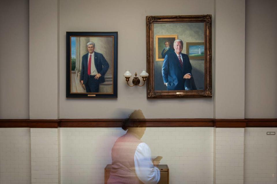 A woman moves past a portrait of former Mississippi governor Haley Barbour (right) at the Mississippi State Capitol in Jackson.