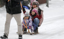 A man pulls his family on a sled at a snowy street in Gelsenkirchen, Germany, Sunday, Feb. 7, 2021. Snow falls extremely seldom in the industrial Ruhr area. (AP Photo/Martin Meissner)