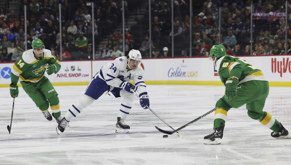 Toronto Maple Leafs center Auston Matthews (34) goes after the puck against Minnesota Wild defenseman Jake Middleton (5) during the second period of an NHL hockey game Friday, Nov. 25, 2022, in St. Paul, Minn. (AP Photo/Stacy Bengs)